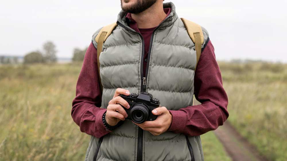 Un photographe qui porte une veste sans manches de type bodywarmer en extérieur. 